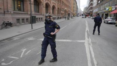 Miembros de la policía sueca se ajustan las máscaras antiguas en la zona donde un camión que ha atropellado a varias personas y se ha estrellado contra una tienda de la calle comercial de Drottninggatan en el centro de Estocolmo. Foto: EFE