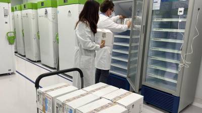 Imagen de dos técnicos de laboratorio guardando dosis de la vacuna de AstraZeneca. EFE
