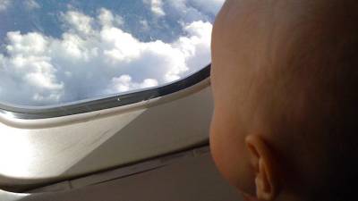 Un bebé mira por la ventana de un avión