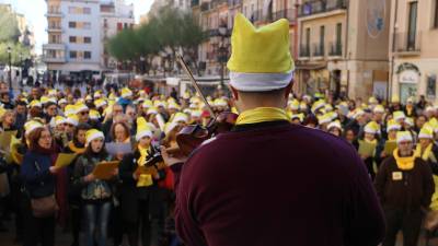Un membre de 'Músics per la llibertat' toca el violí, d'esquenes, davant de desenes de persones a la plaça de la Font de Tarragona a la cantada de nadales per la llibertat. FOTO: ACN