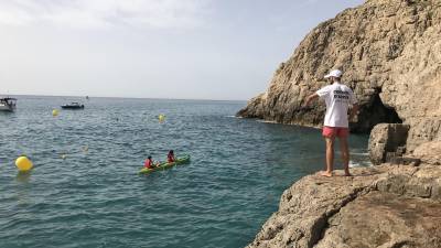 Un kayak con dos personas se dirige hacia la Cova del Llop Marí ante el operario que controla el acceso. foto:cedida