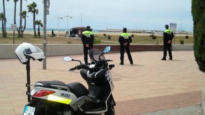 Policías locales vigilan a un grupo de manteros que está en la playa.