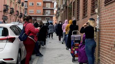 Varias personas aguardan su turno para entrar al economato de Cáritas en el distrito madrileño de Tetuán.  FOTO: CAÑAS/EFE