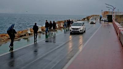 Taxis y turistas caminando, a pesar del mal tiempo, por el Passeig de l’Escullera, tras bajar del crucero. FOTO: lluís milián