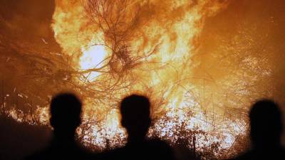 Unes persones observen un incendi a Chandebrito (Galícia), dilluns passat. Foto: EFE