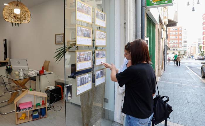 Dos jóvenes comentan las ofertas de una inmobiliaria, en Tarragona. Foto: Pere Ferré