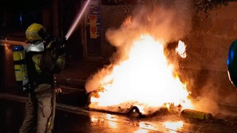 Un bombero apagando uno de los coches quemados. Foto: Bombers de la Generalitat