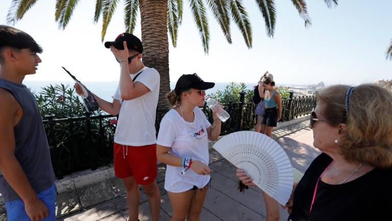 Turistas, con abanicos, agua y bajo la sombra, refrescándose ayer en el Balcó del Mediterrani. Foto: Pere Ferré