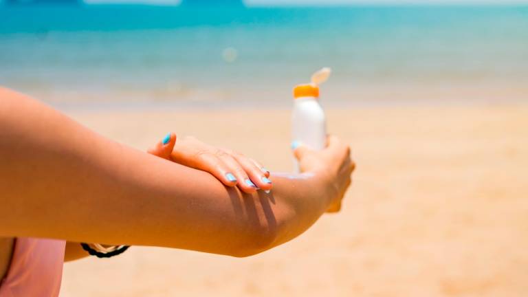 La exposición indiscriminada al sol es una de las causas de lupus. FOTO: GETTY IMAGESGirl applying sun lotion on her hands at the beach