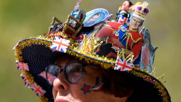 Británicos y turistas extranjeros, portando banderas del Reino Unido, gorras y pancartas, aguardan el comienzo del espectáculo de la coronación. Foto: EFE