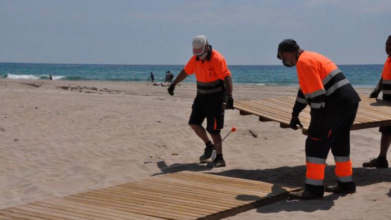 Operarios de la brigada colocando los pasos de madera en la playa. FOTO: Anna F.-Aj. Torredembarra