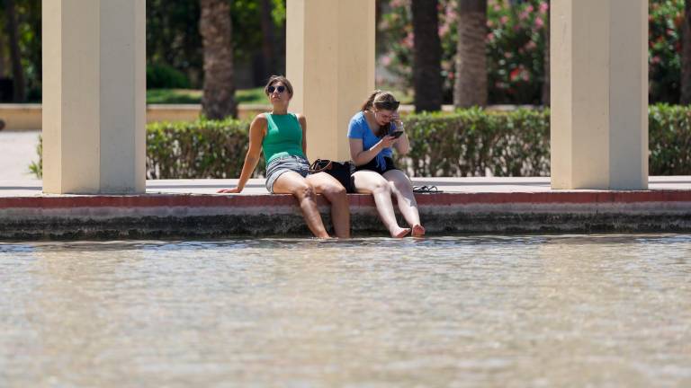 Dos personas se refrescan en una fuente de los jardines del antiguo cauce del Turia para combatir el calor que vive durante este lunes. Foto: EFE