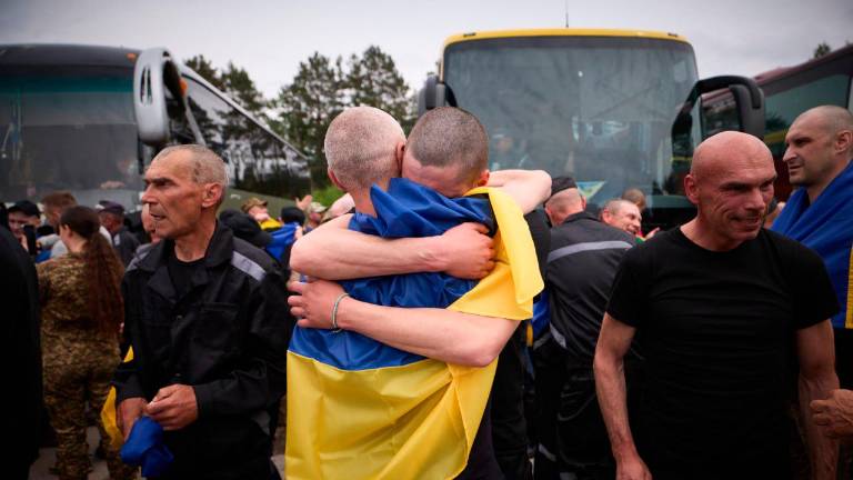 Prisioneros ucranianos intercambiados en virtud de un acuerdo entre Rusia y Ucrania se abrazan al ser liberados, envueltos en la bandera ucraniana. Foto: Gobierno de Ucrania