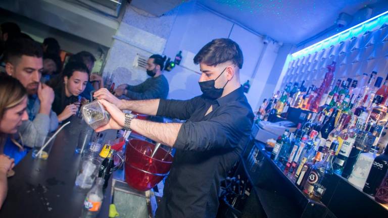 Un camarero, con la mascarilla colocada mientras sirve una copa, tras la barra de la discoteca Totem. foto: totem