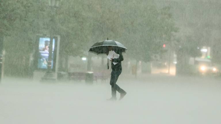Un hombre camina bajola intensa lluvia este viernes en Valencia. FOTO: EFE