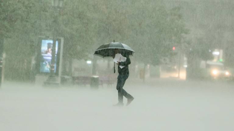 Un hombre camina bajola intensa lluvia este viernes en Valencia. FOTO: EFE