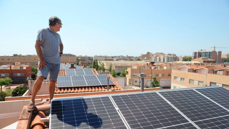 Un vecino del barrio La Mineta junto a las placas solares de su casa y otras del vecindario visibles, también. Foto: Alba Mariné