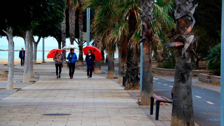Tres dones passegen amb paraigües pel passeig marítim de Cambrisl. FOTO: ACN