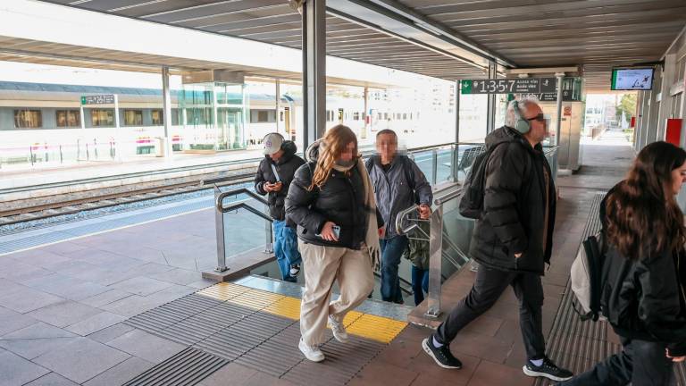 Usuarios en la estación de Renfe de Reus con paneles de fondo. Foto: Alba Mariné