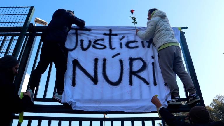 Dos trabajadores de Mas d’Enric colgando una pancarta tras el asesinato de Núria. Foto: ACN