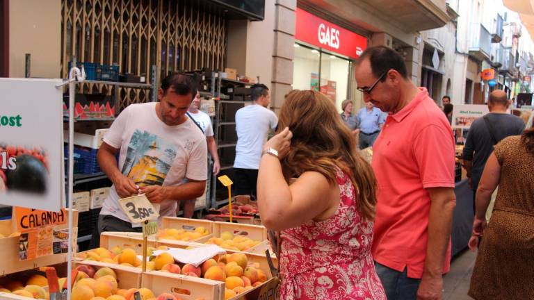 Dues persones aprofitant per comprar al carrer la Cort fruita dels pagesos que hi havia. Foto: Marina Pérez