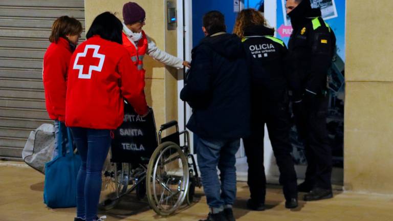 Una patrulla de la Guàrdia Urbana de Tarragona y voluntarios de Creu Roja acompañan hasta el alojamiento donde pasarán en las próximas noches dos personas sin techo, una de las cuales necesita moverse en silla de ruedas. Foto: ACN