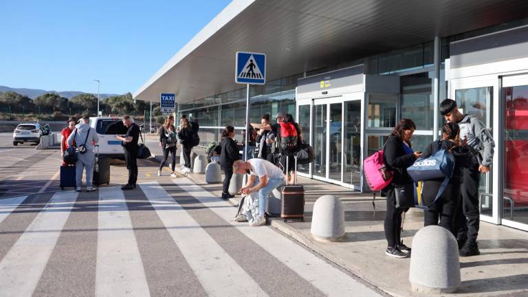 Algunos pasajeros en el exterior del edificio del Aeropuerto de Reus, en la zona de llegadas, donde los taxis esperan para cargar. Foto: Alba Mariné