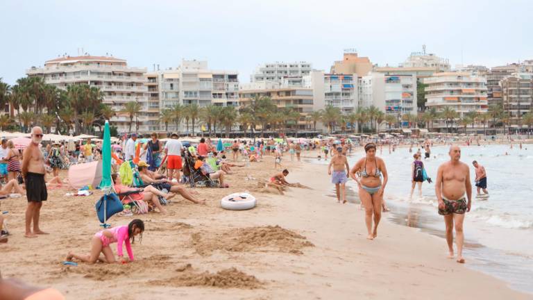 Numerosos turistas disfrutan de la playa de Llevant de Salou, con edificios de apartamentos y hoteles al fondo. Foto: Alba Mariné