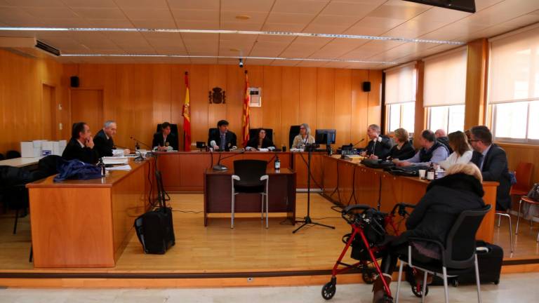 Tres personas acusadas de un delito continuado de estafa y blanqueo de capitales, de espaldas, y sus abogados en la vista celebra a la Audiencia de Tarragona. Foto: ACN
