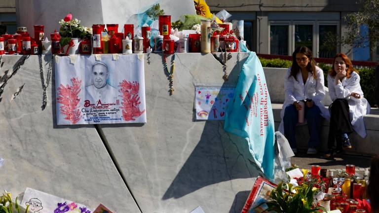 Médicos se sientan frente a la estatua de Juan Pablo II en la entrada del Hospital Gemelli, donde el papa Francisco está hospitalizado, en Roma. Foto: EFE