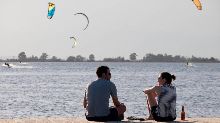 Una parella a la platja del Trabucador, amb surfistes d’estel de fons. FOTO: J. Revillas