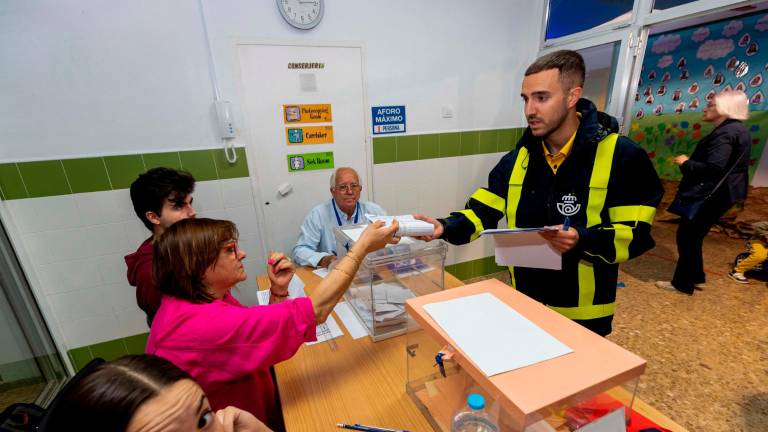 Un cartero entrega a la presidenta de una mesa electoral el voto por correo que corresponde a esa mesa, este pasado domingo en el colegio de San José de Lorca. Foto: EFE