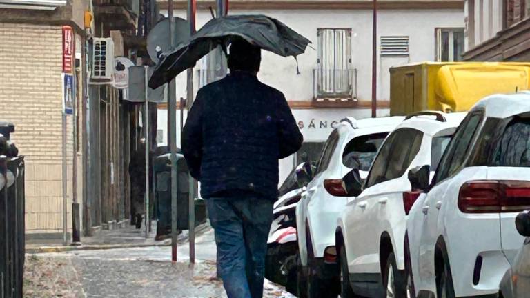 Un hombre camina con el paraguas casi destrozado por la calle. Foto: EFE
