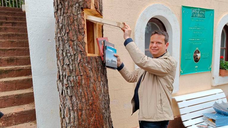 L’alcalde de Cambrils dipositant llibres en un dels troncs del Parc Samà. FOTO: cedida