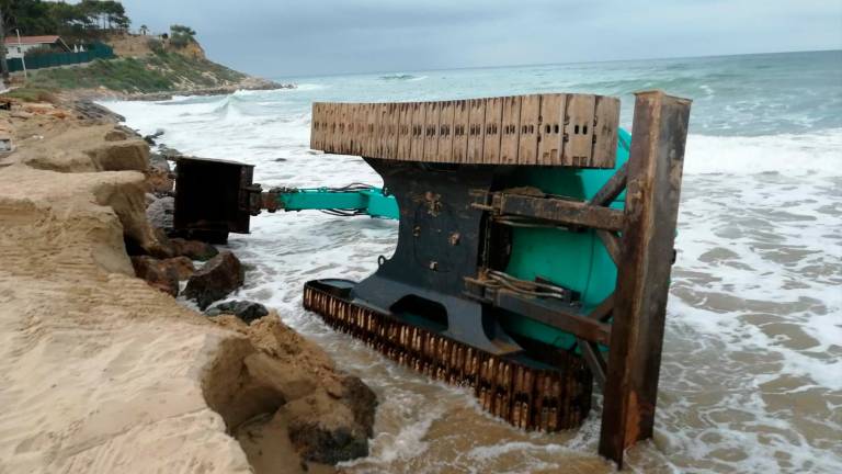 La excavadora ha terminado de lado al llevarse el mar la arena que estaba debajo de sus cadenas. FOTO: Cedida