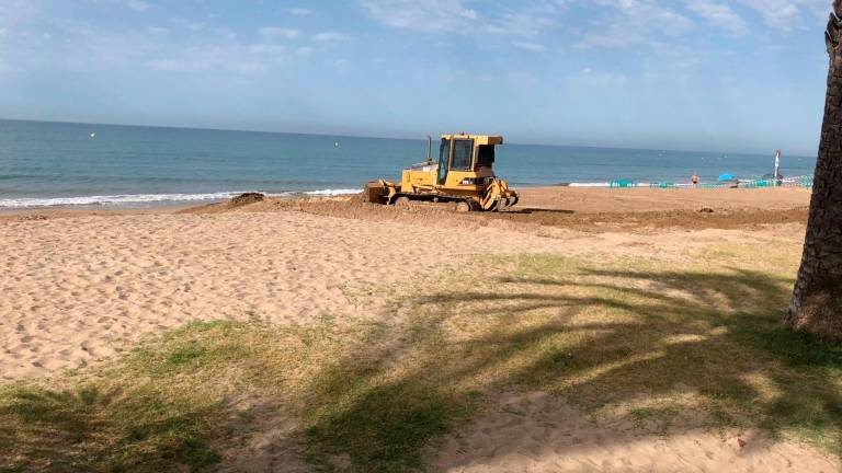 La excavadora arrastra arena para suavizar la orilla.