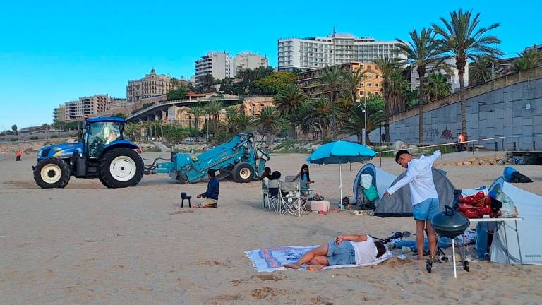 Dos grupos de personas acampadas en el Miracle mientras pasa a su lado la máquina de la limpieza. Foto: N.M.