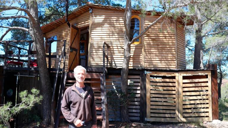 Thierry Martinet con la cabaña del árbol de Cal Galeno, un alojamiento turístico 100% autosuficiente. Foto: Roser Urgell