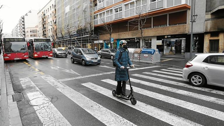 Imagen de un usuario de patinete eléctrico circulando por la ciudad con casco. FOTO: PERE FERRÉ