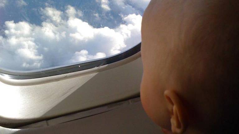 Un bebé mira por la ventana de un avión