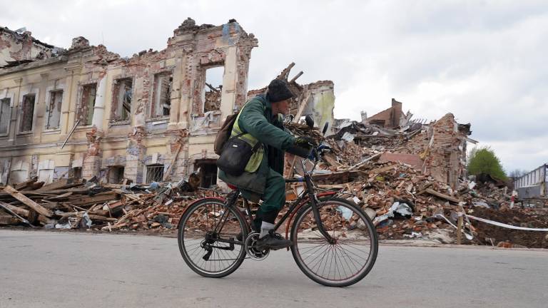 Una persona en bicicleta, delante de un edificio derruido en Ucrania. Foto: EFE
