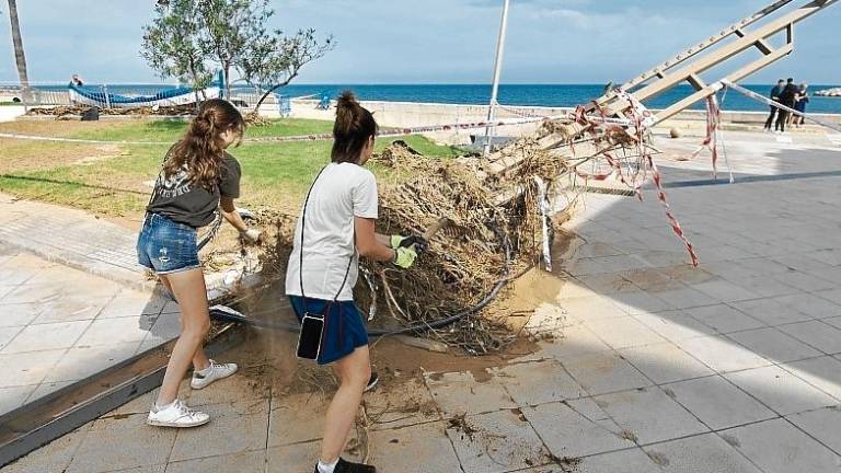 Dos joves netejant encara el fang i la vegetació, aquest dilluns a la façana marítima de les Cases d’Alcanar. foto: Joan Revillas