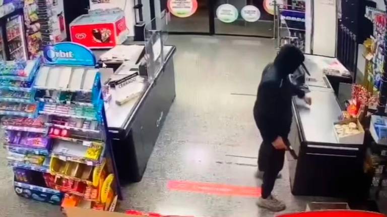 El ladrón, empuñando el arma, mientras amenazaba a la cajera. Foto: Instagram
