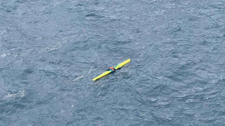 El kayakista, encima de la tabla antes de ser rescatado por el helicóptero. Foto: Salvamento Marítimo