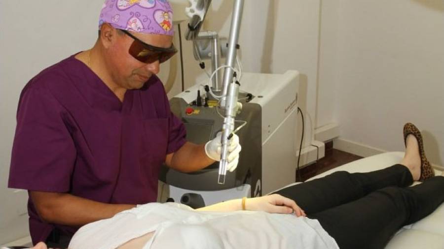 El Dr. Carlos Sarmiento Ardaya en una sesión mostrando cómo se quita un tatuaje de una paciente