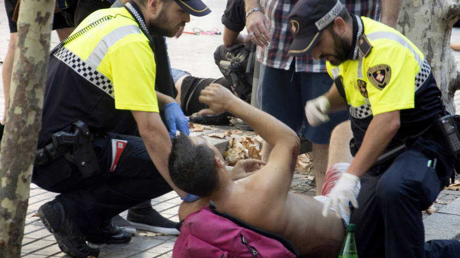 Efectivos policiales atienden a una de las v&iacute;ctimas de un atropello masivo de una furgoneta que ha arrollado esta tarde a varias personas que paseaban por las Ramblas de Barcelona