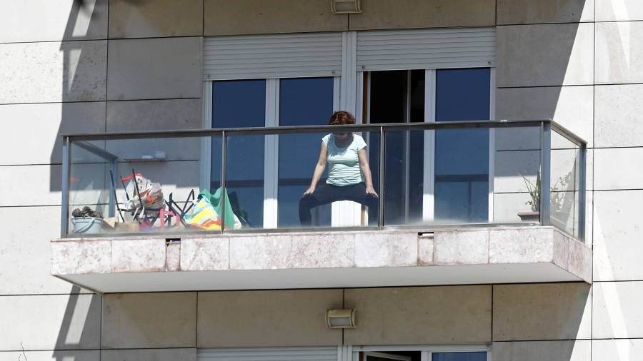 Una mujer hace ejercicio en el balcón. Una de las entrevistadas sigue los ejercicios de un vecino. FOTO:EFE