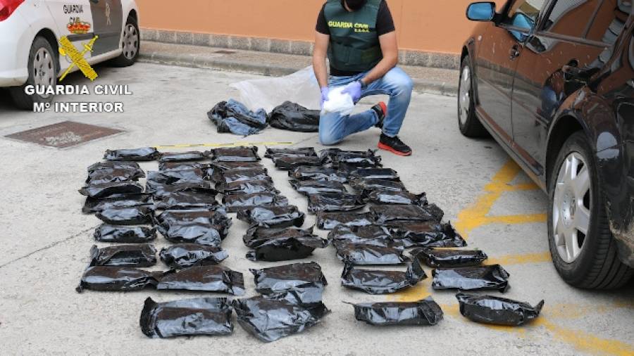 Un agente de la Guardia Civil muestra diversos paquetes de droga incautados