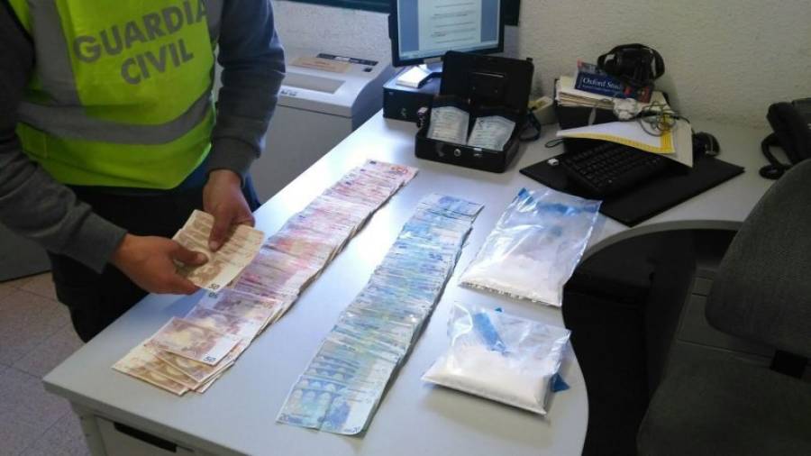 Un agent fa el recompte dels diners trobats en aquest pis de Móra d´Ebre. Al costat, dues bosses amb les pastilles decomissades. Foto: Guàrdia Civil