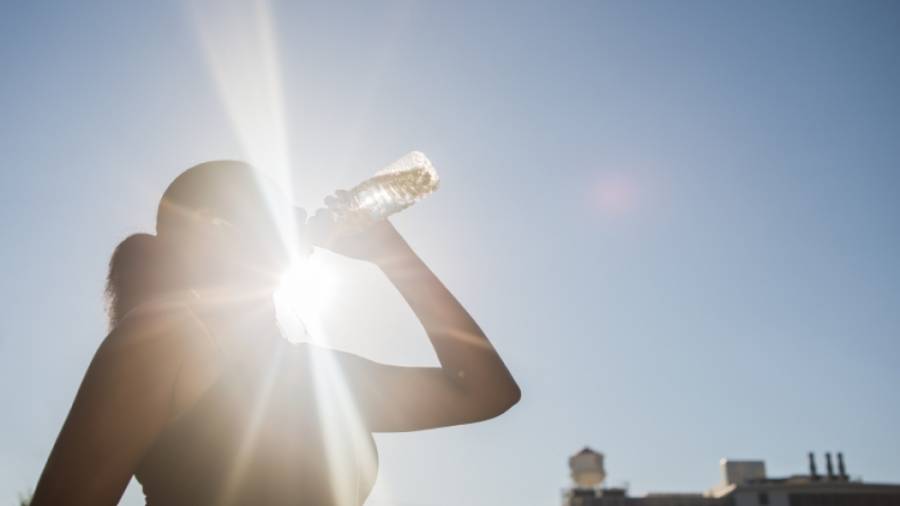 Una mujer bebe agua bajo el sol radiante del verano